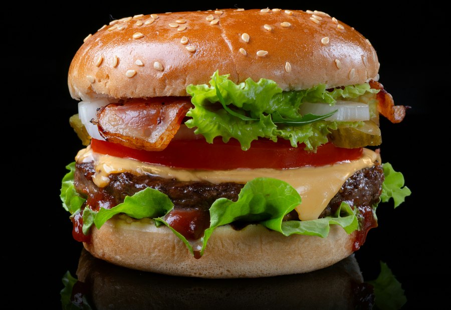 A stacked burger with cheese and fresh toppings.